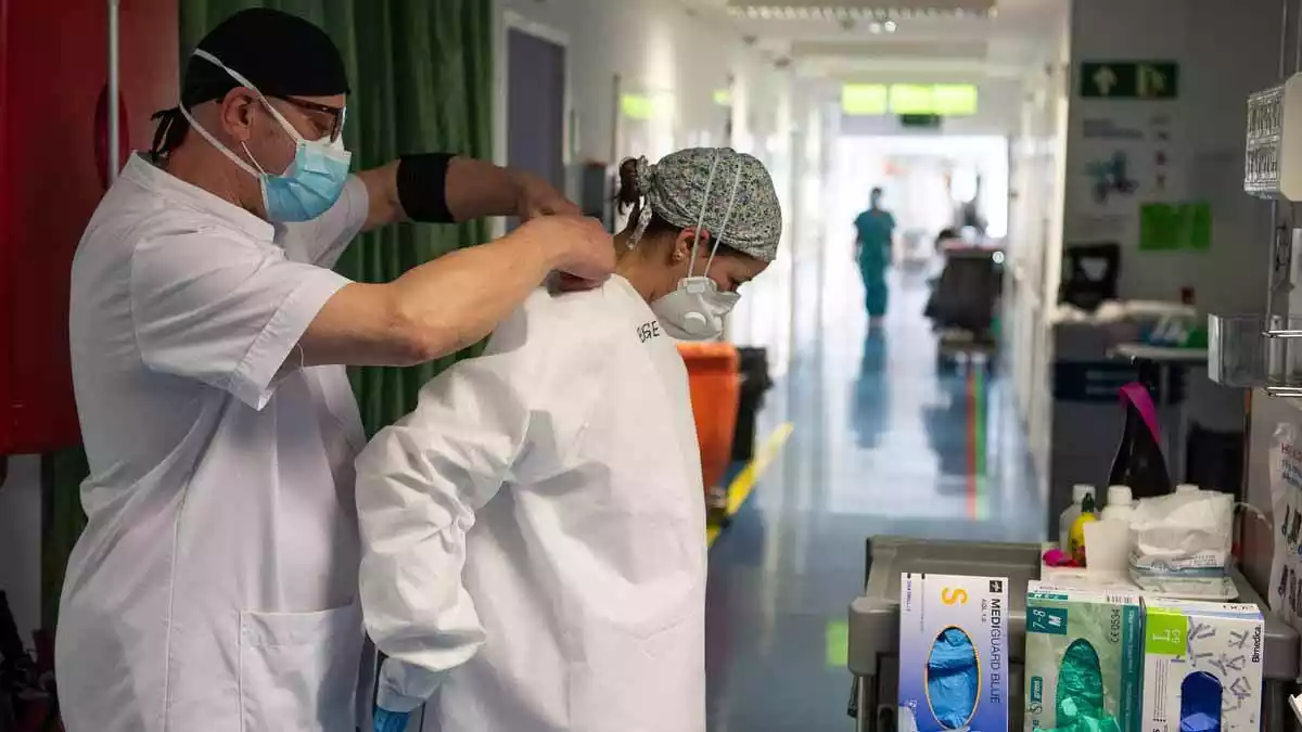 Sanitaris ajudant-se a posar l'equip de protecció contra el coronavirus a l'Hospital Clínic
