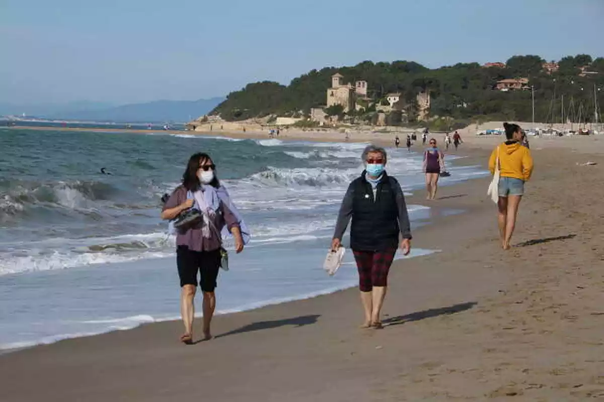 Pla general de dues dones amb mascareta caminant per la platja d'Altafulla en el primer dia permès per sortir a practicar esport.