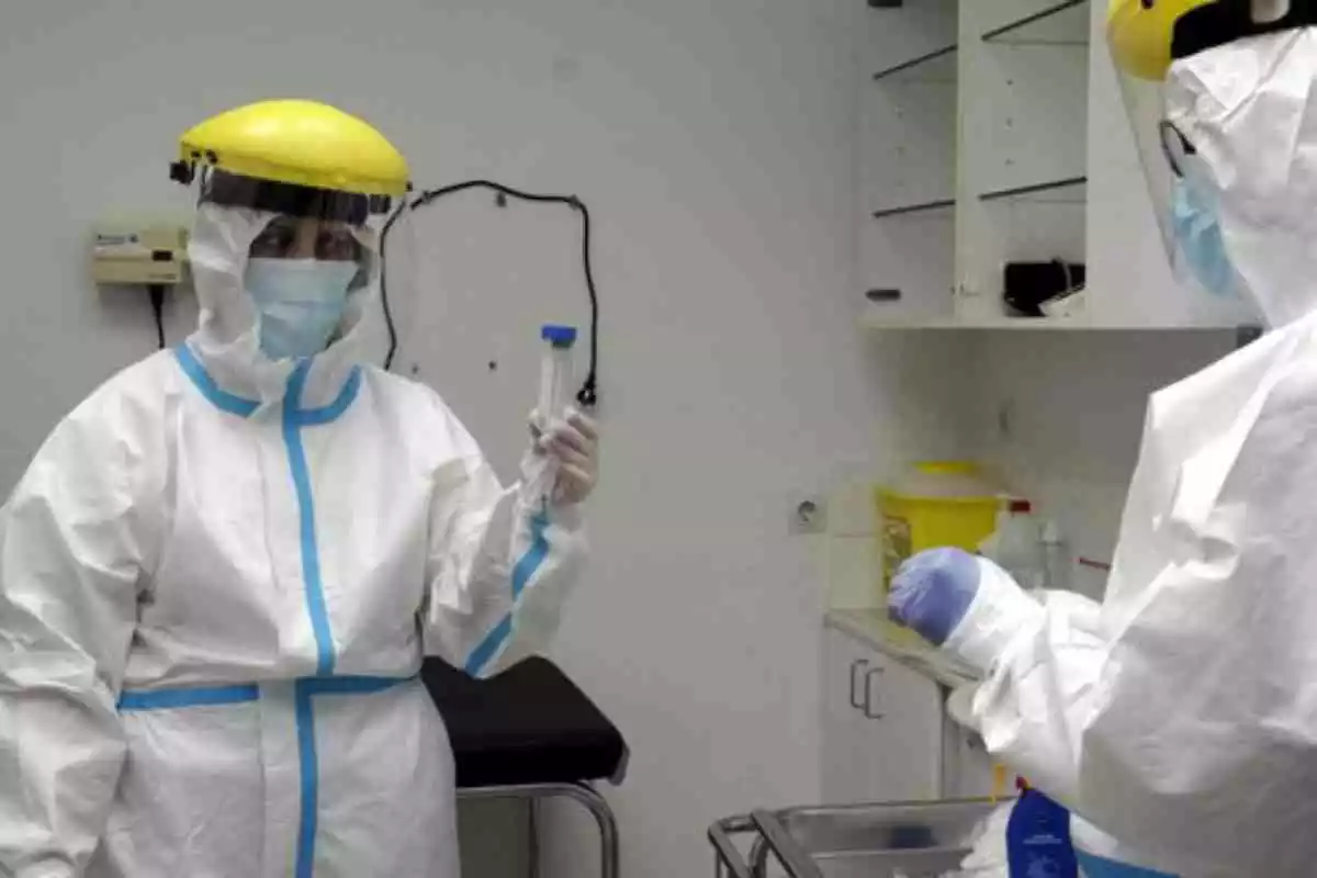 Dues persones amb vestimenta especial per al coronavirus en un laboratori