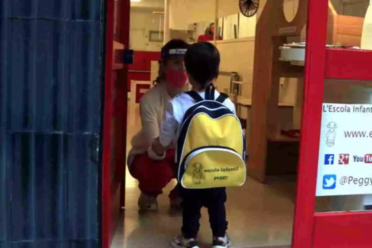 Un alumne a l'entrada de la seva escola davant la professora