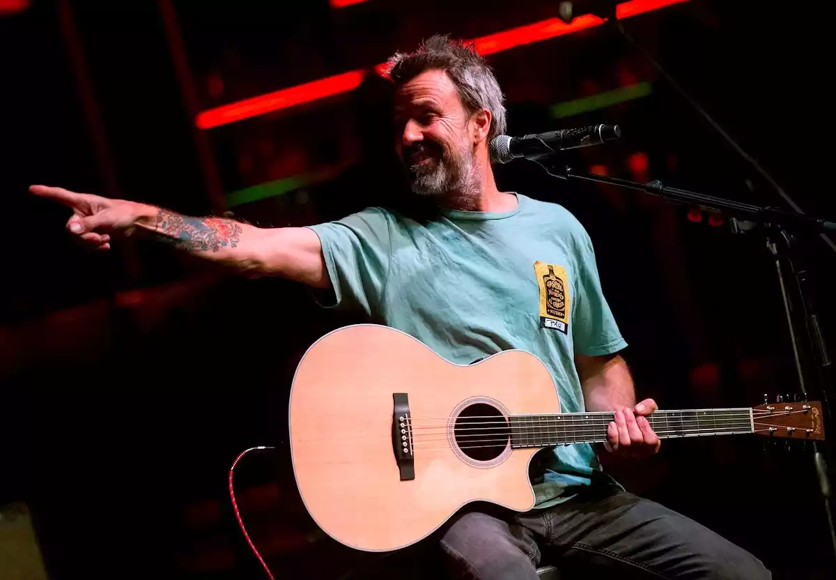 Imatge de Pau Donés, vestit amb una samarreta de color verd i guitarra en mà, durant un concert