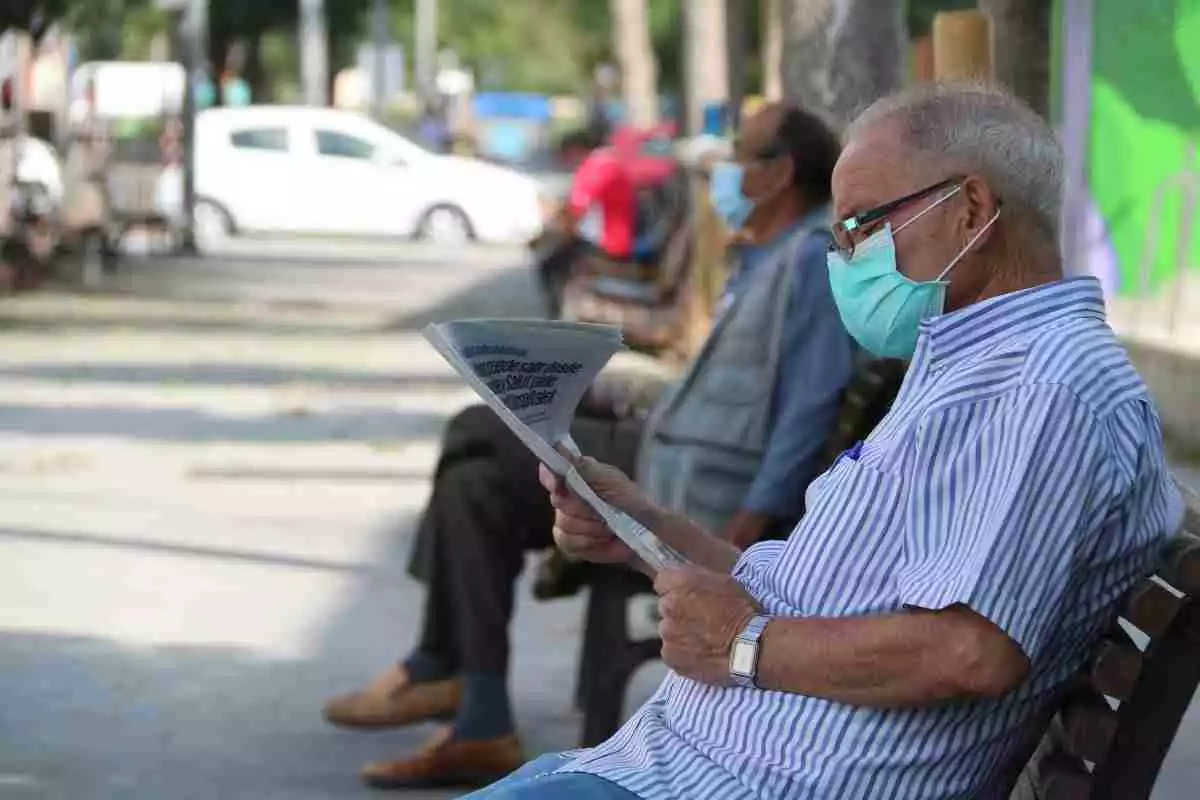 Imatge d'un home llegint el diari en un banc al barri de la Florida de l'Hospitalet de Llobregat