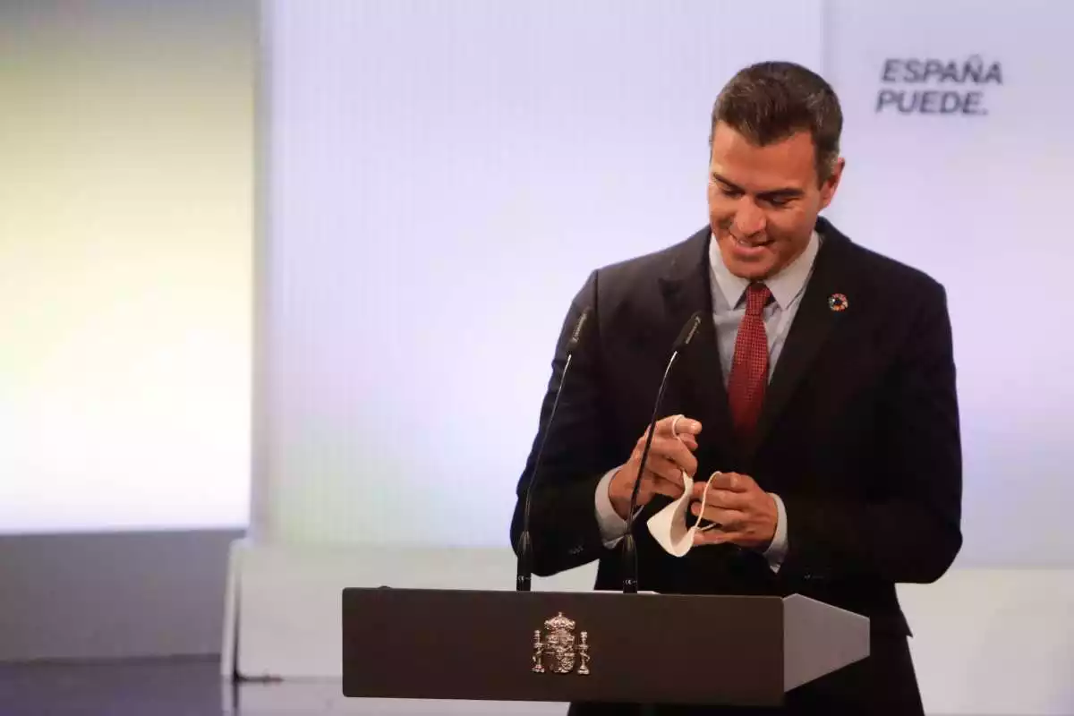 Pedro Sánchez durant una compareixença, en primer pla i somrient amb el micròfon davant