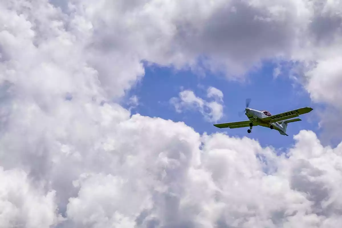 Una avioneta sobrevolando el cielo bajo las nubes