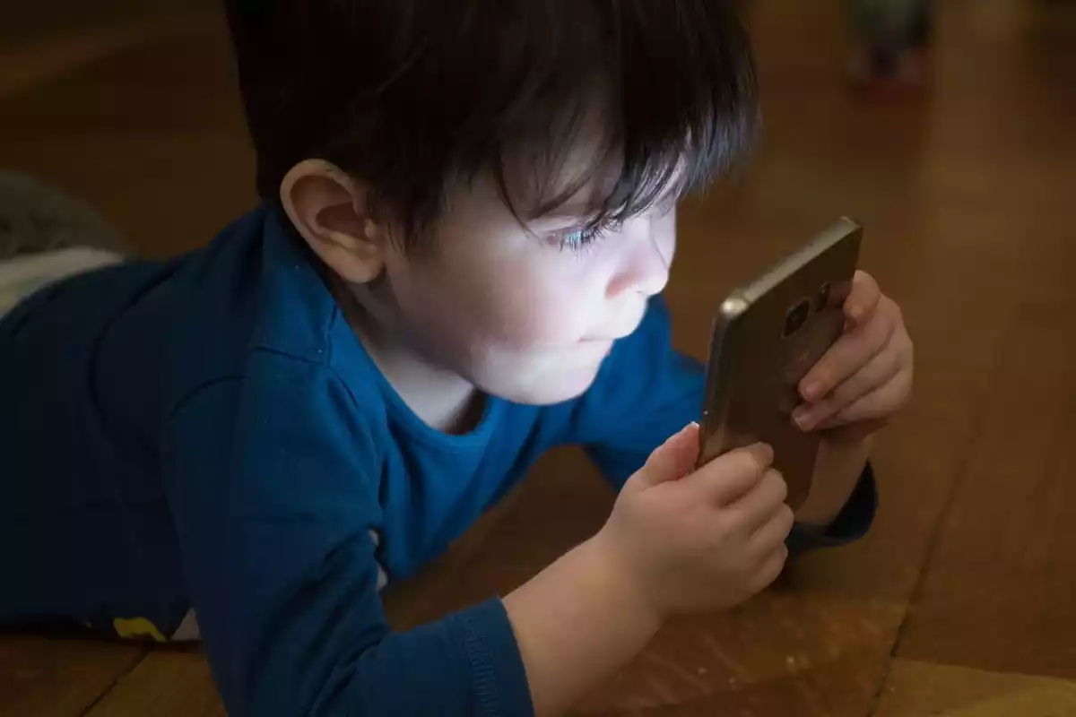 Un niño sujeta un teléfono móvil en las manos