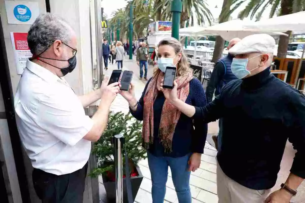 Un camarero pide certificado a los clientes en la puerta de un bar durante el primer día de petición de Certificados Covid-19 en Málaga