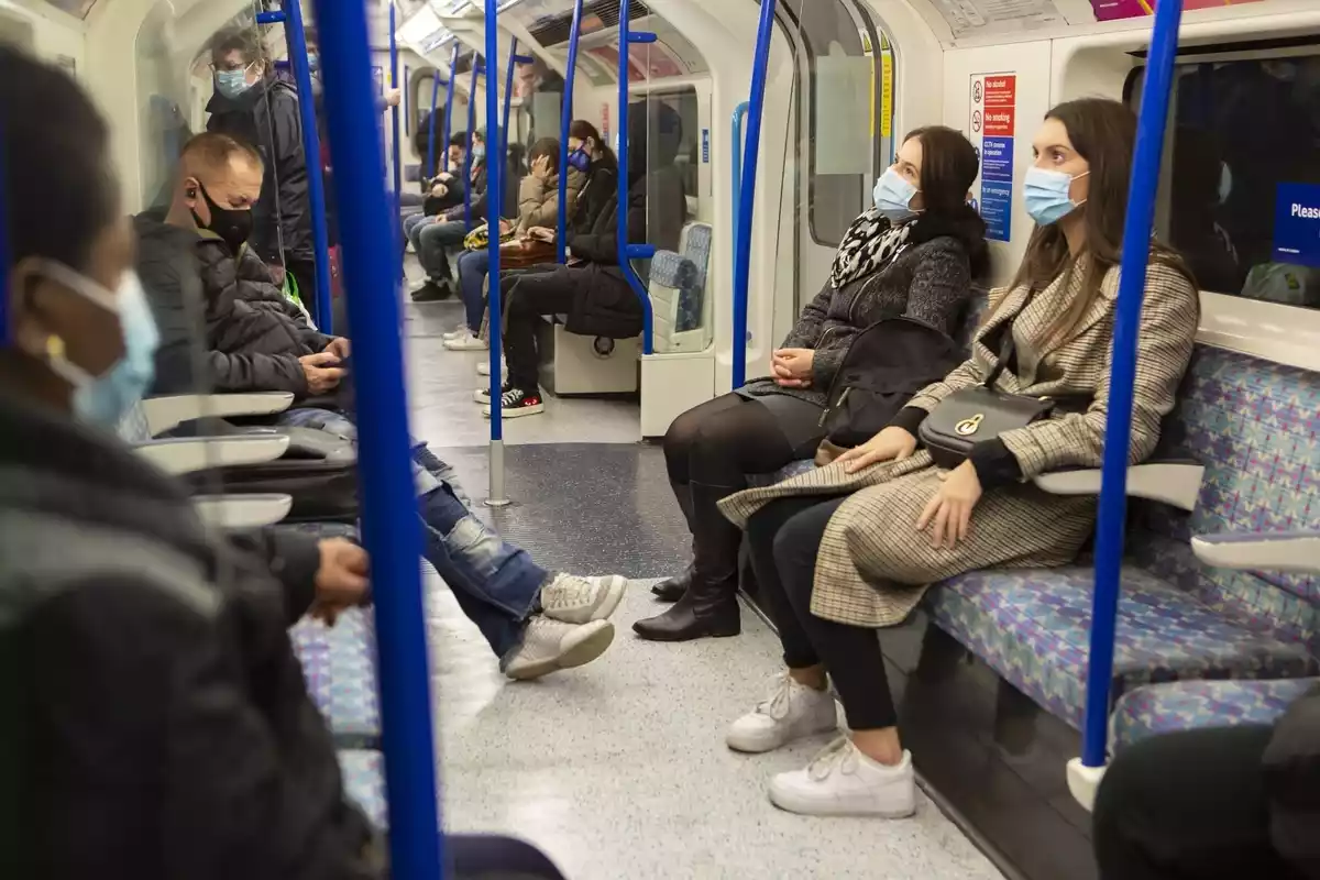 Varias personas haciendo un viaje en metro con mascarillas puestas