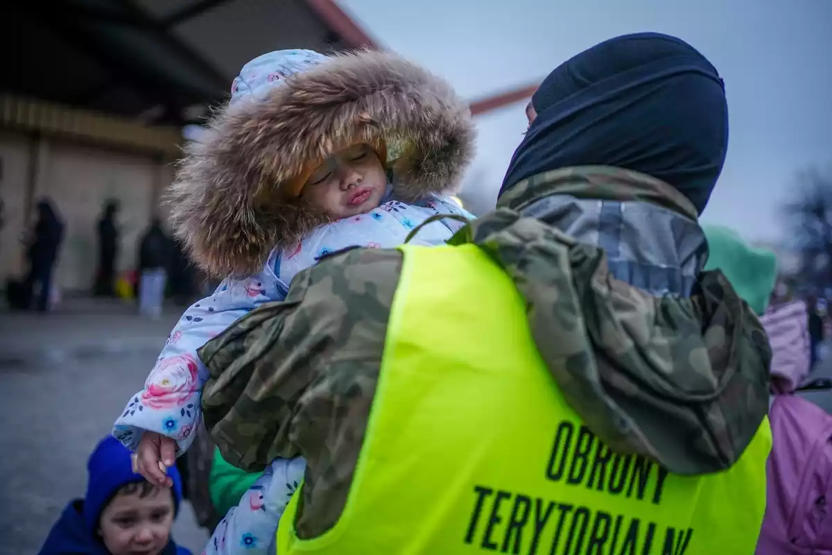 Una niña ucraniana refugiada en los brazos de una autoridad tras el ataque de Rusia