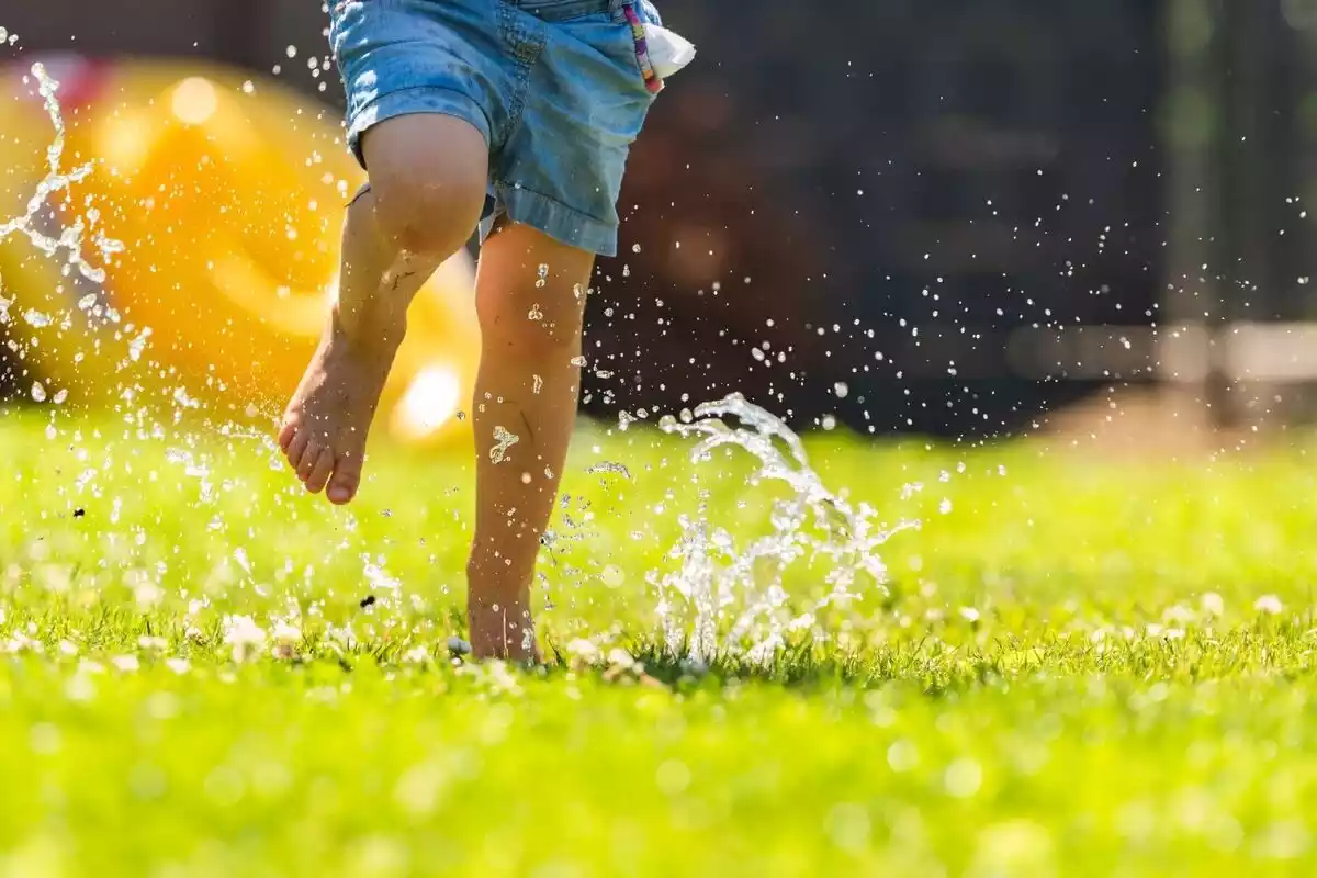 Imagen de las piernas de un niño corriendo por un jardín