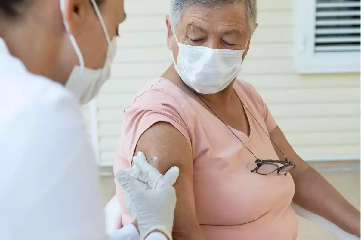 Una sanitaria vacunando a una persona mayor.