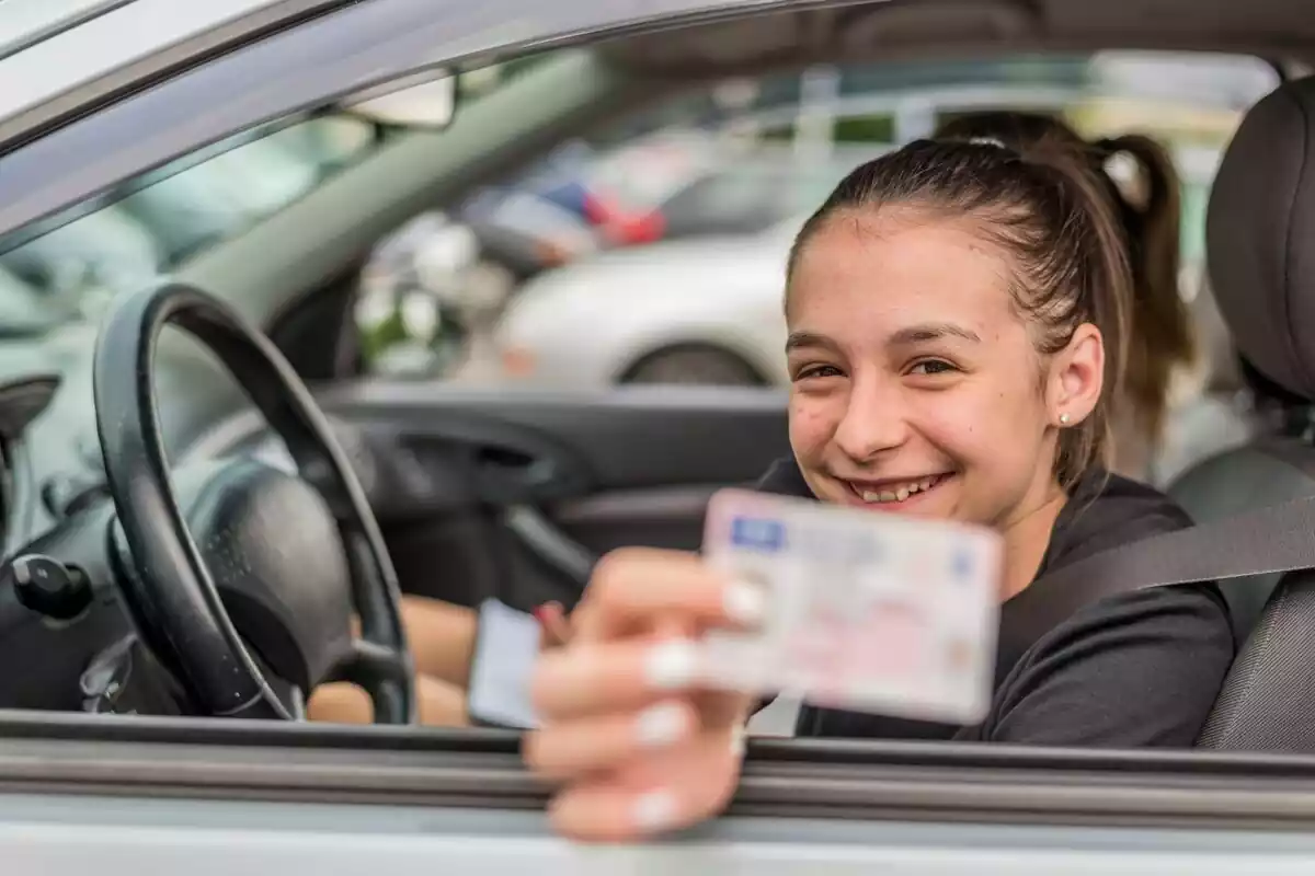 Foto de una adolescente enseñando su carné de conducir