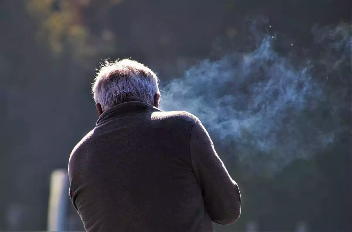 Un hombre de espaldas rodeado de humo de un cigarro