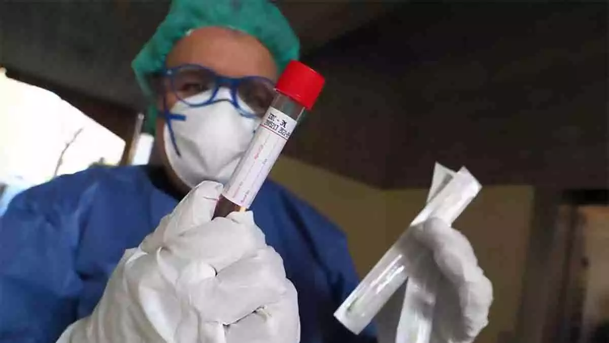 Médico con mascarilla sosteniendo una muestra de sangre