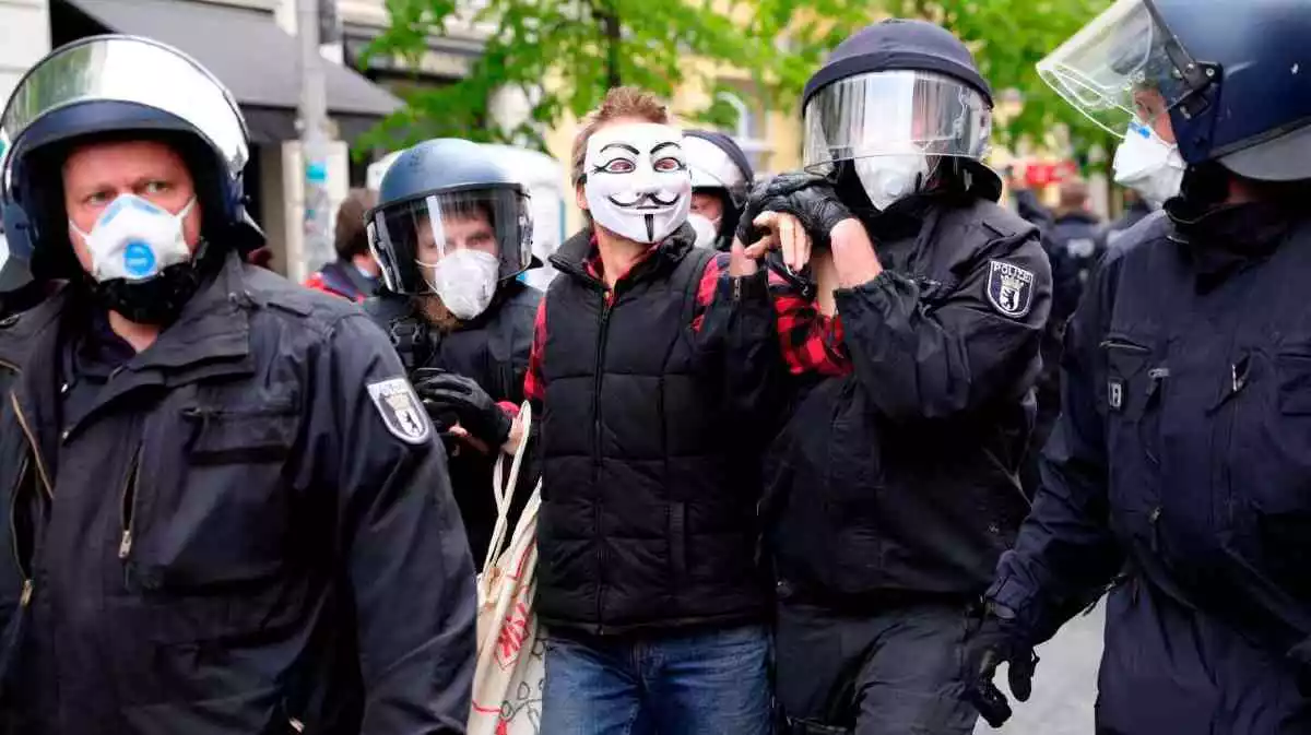 La policía alemana dotada de todo el material de protección desaloja a un participante en una concentración este sábado en Berlín.