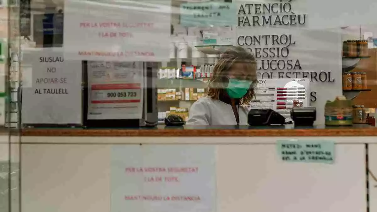 Imagen de una farmacia con una farmacéutica con mascarilla durante el estado de alarma por el coronavirus