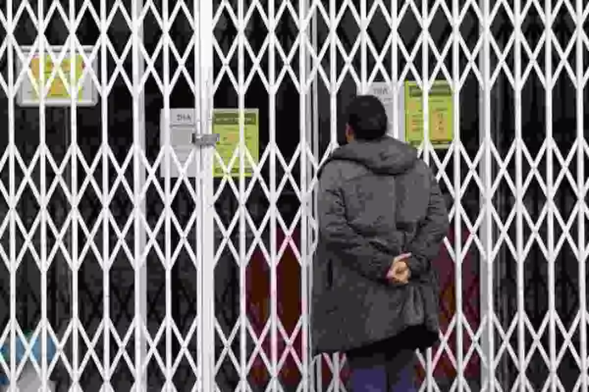 Una persona enfrente de un comercio con las puertas cerradas durante el Coronavirus