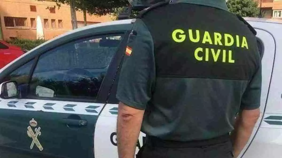 Agente de la Guardia Civil en servicio junto a un coche de patrulla del cuerpo