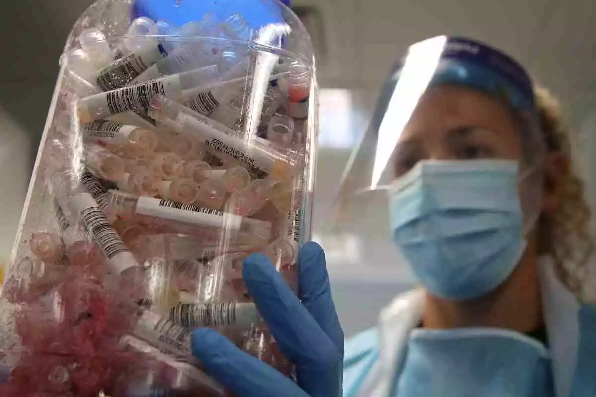 Enfermera con un bote lleno de pruebas PCR de coronavirus, 2020