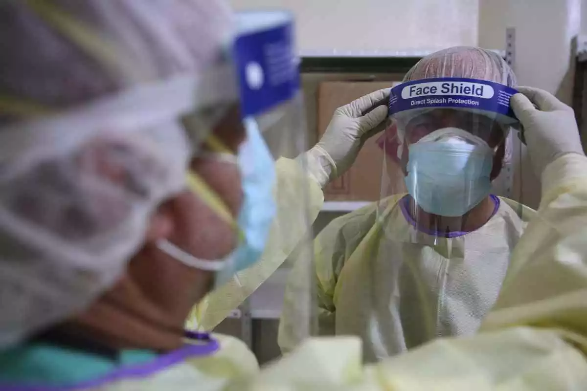 Un médico con un equipo protector completo ajusta una cubierta facial a su compañero en el primer hospital especializado para casos de coronavirus en el norte de Siria