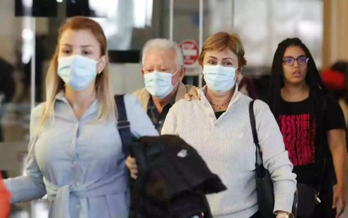 Varios pasajeros con mascarillas en un aeropuerto