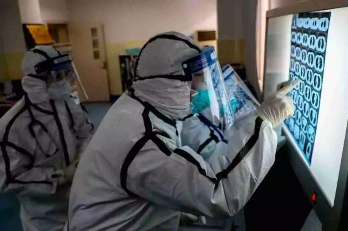 Científicos analizando una placa durante la crisis del Coronavirus con traje de protección