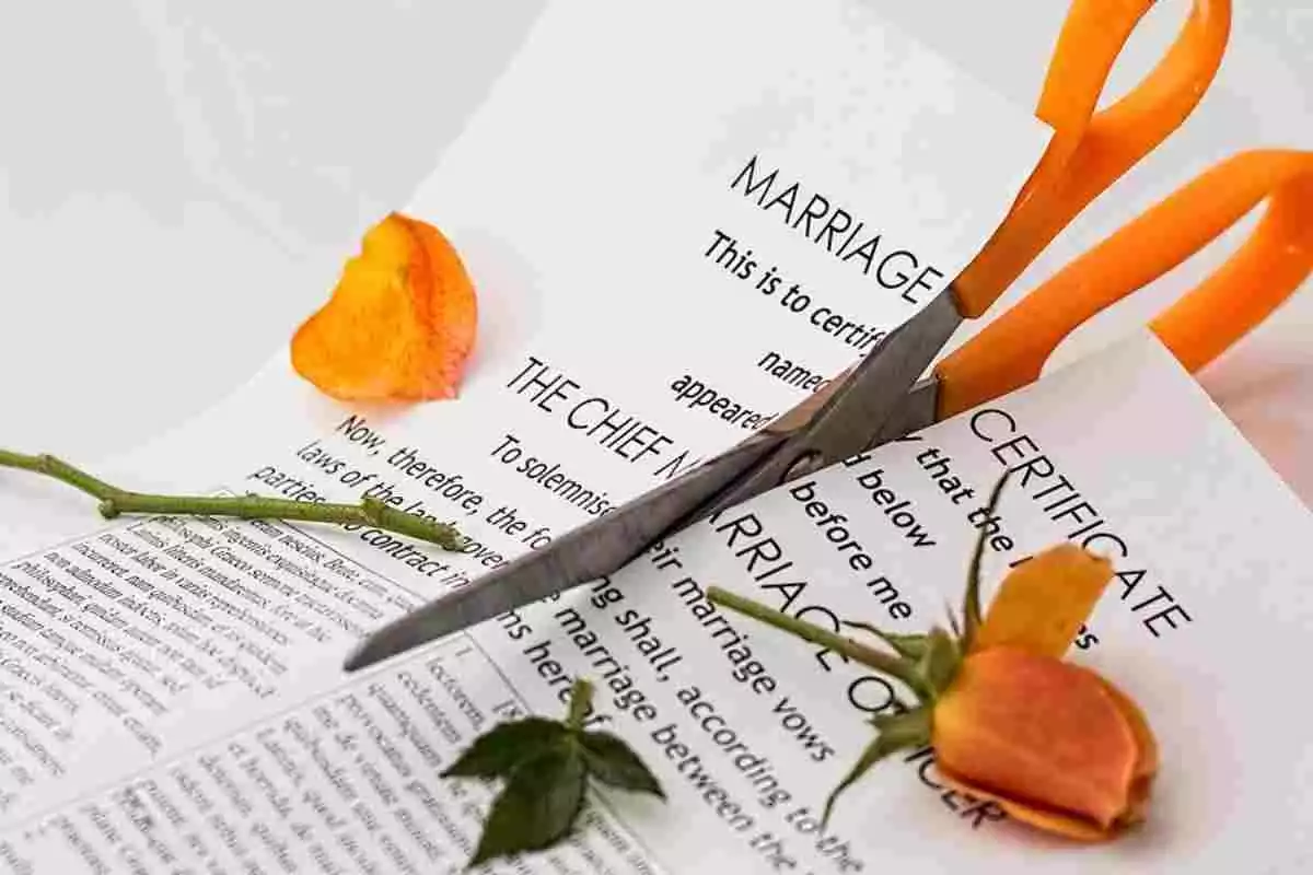 Tijeras cortando un certificado de matrimonio y una rosa