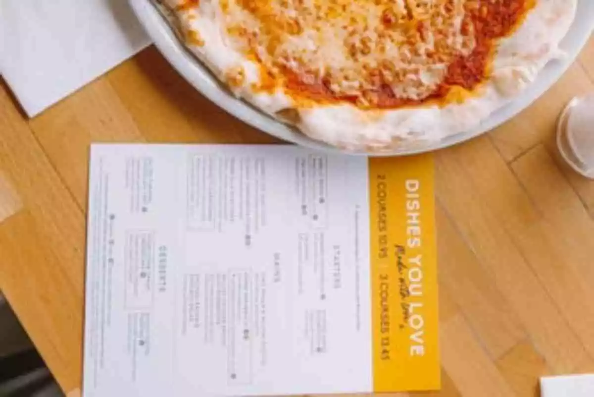 Foto de una mesa con una porción de pizza y una nota
