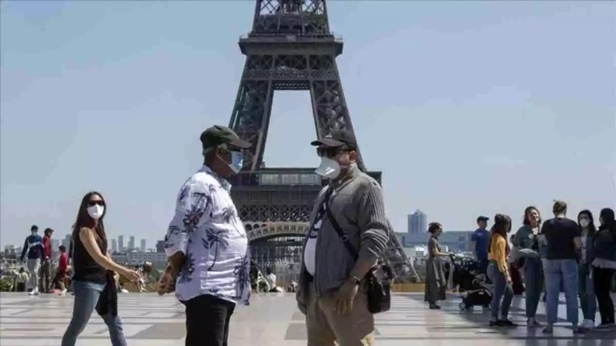 Imagen de personas con mascarilla en la Torre Eiffel en París.