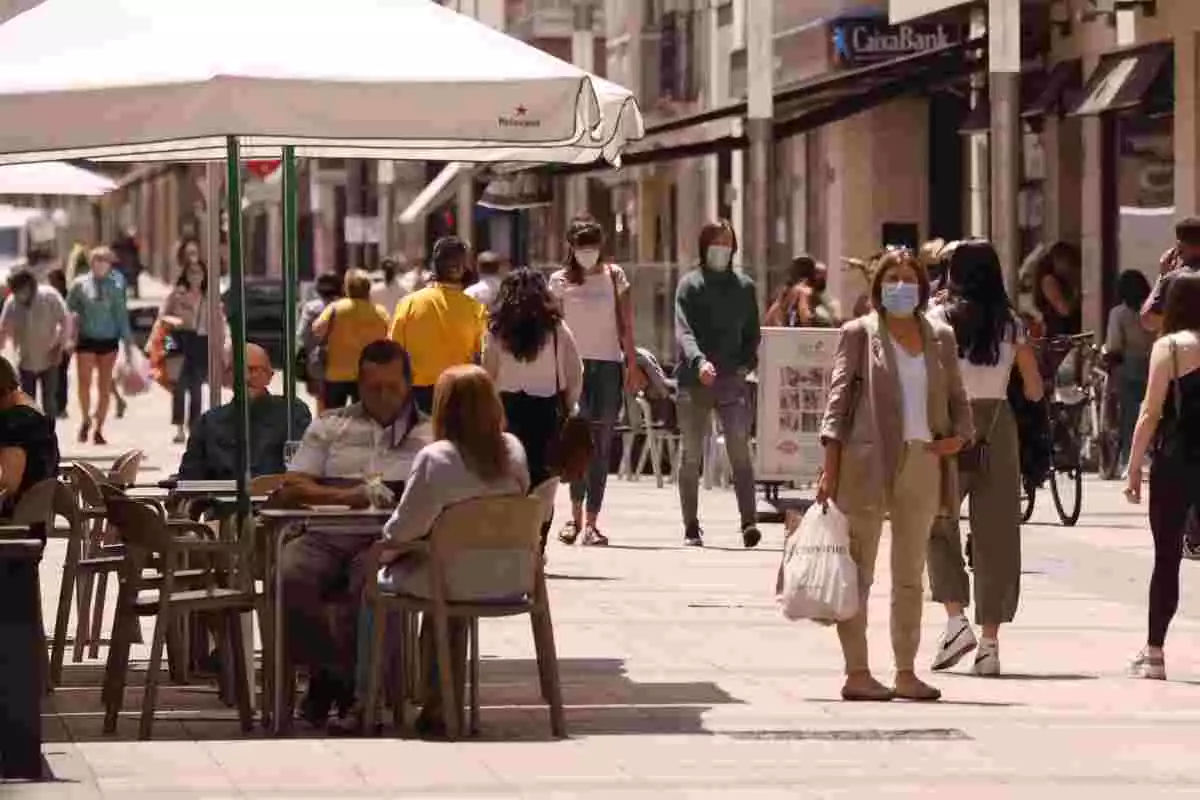 Personas paseando con mascarillas y sentadas en terrazas en una céntrica calle de Vitoria