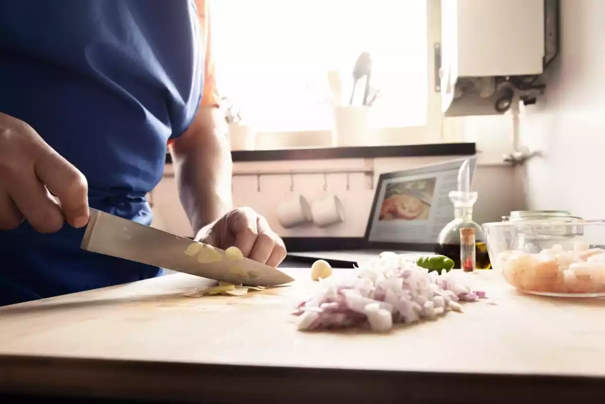 Fotografía de una persona cortando alimentos en una cocina