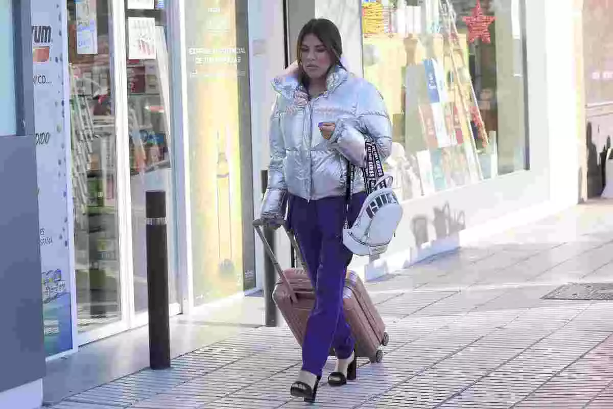 Isa Pantoja paseando con una maleta y una chaqueta plateada