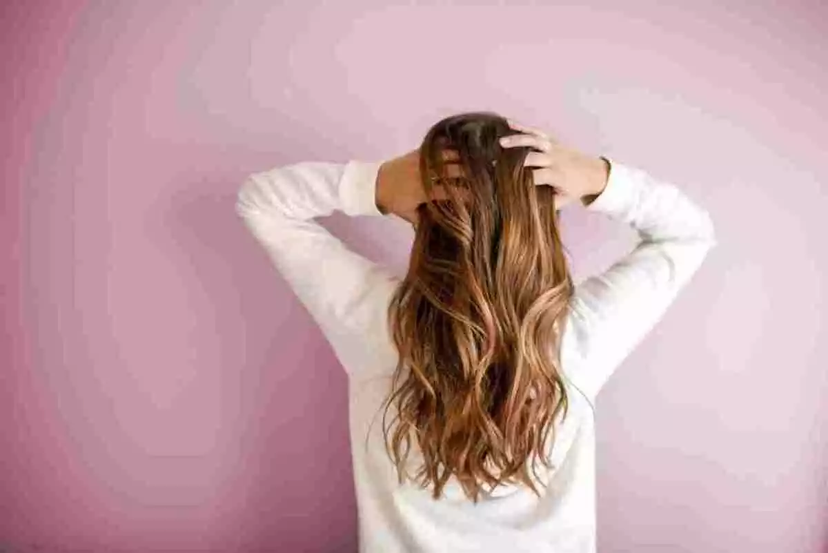Foto de archivo de mujer con melena larga tocándose el pelo