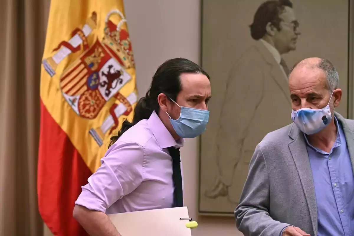 Pablo Iglesias preparando una reunión de gobierno con la bandera nacional de fondo