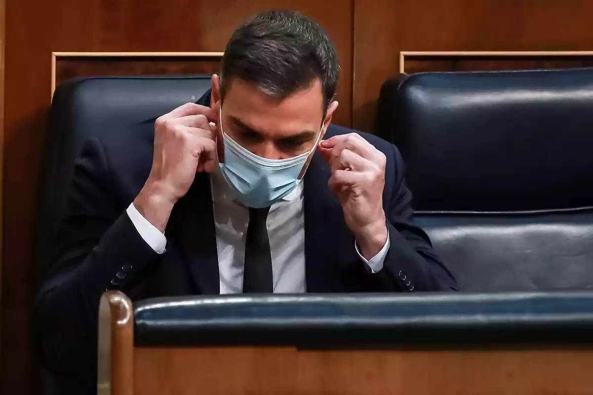 Pedro Sanchez colocándose la mascarilla en su escaño del Congreso de los Diputados