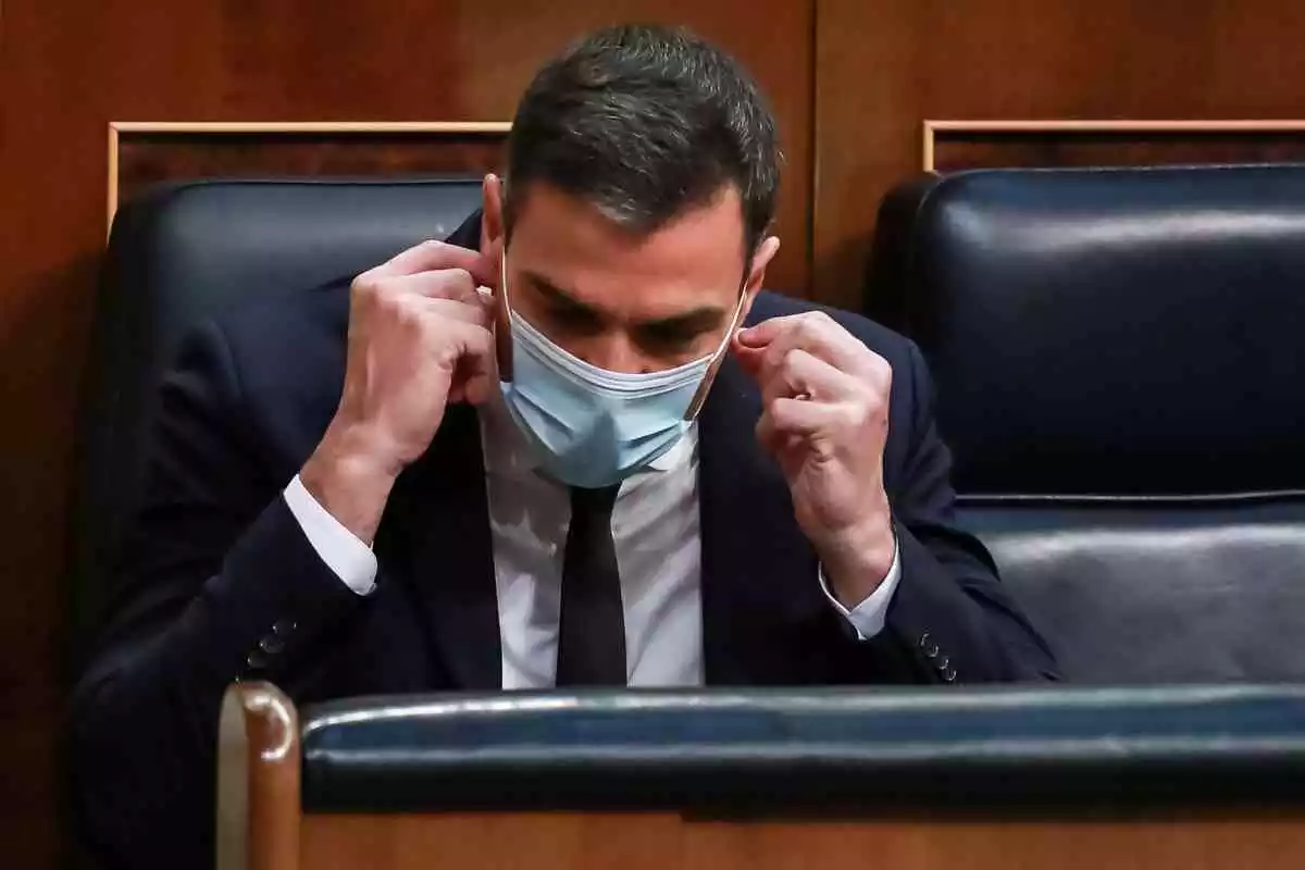 Pedro Sanchez colocándose la mascarilla en su escaño del Congreso de los Diputados