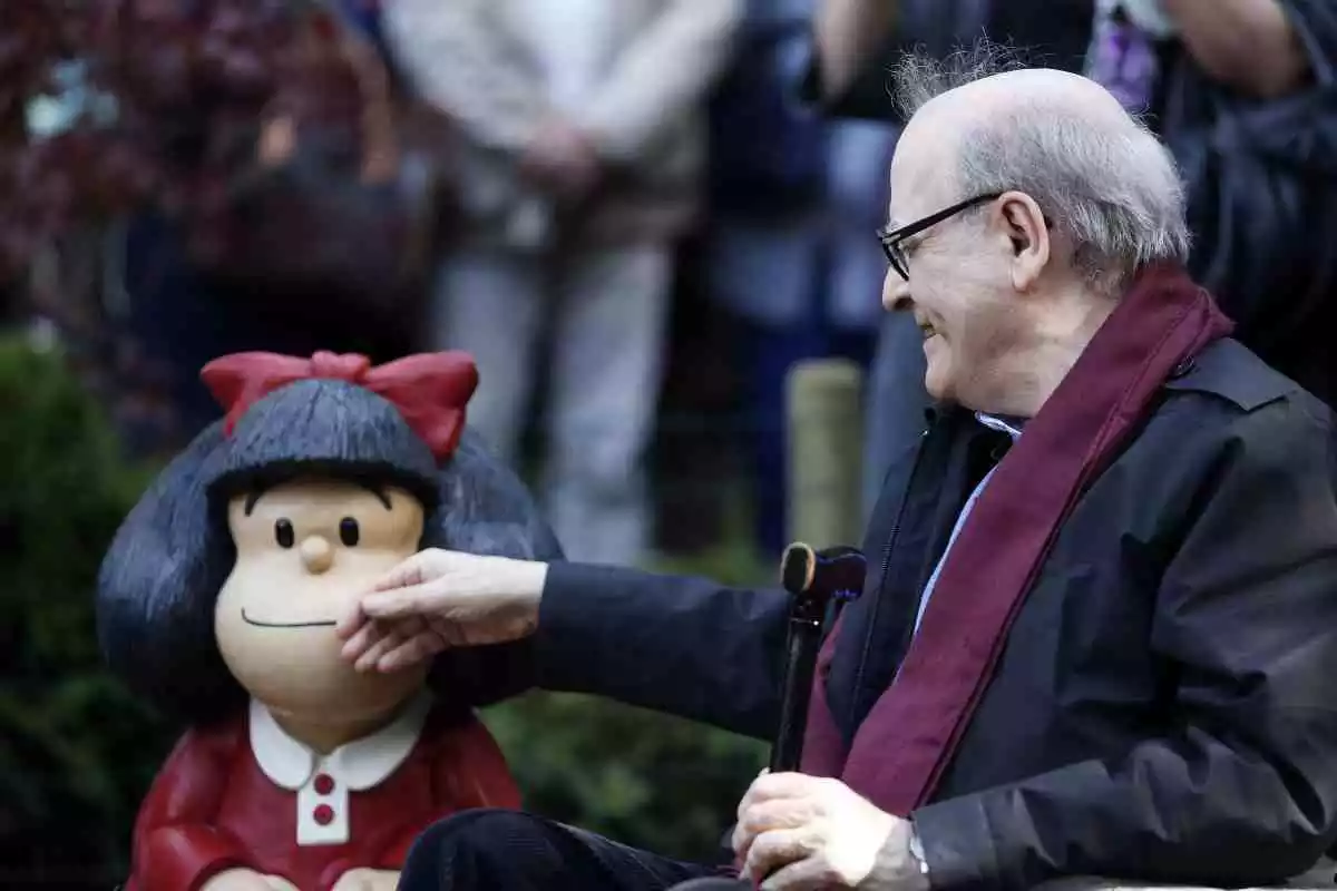 El dibujante Quino tocando un muñeco de Mafalda