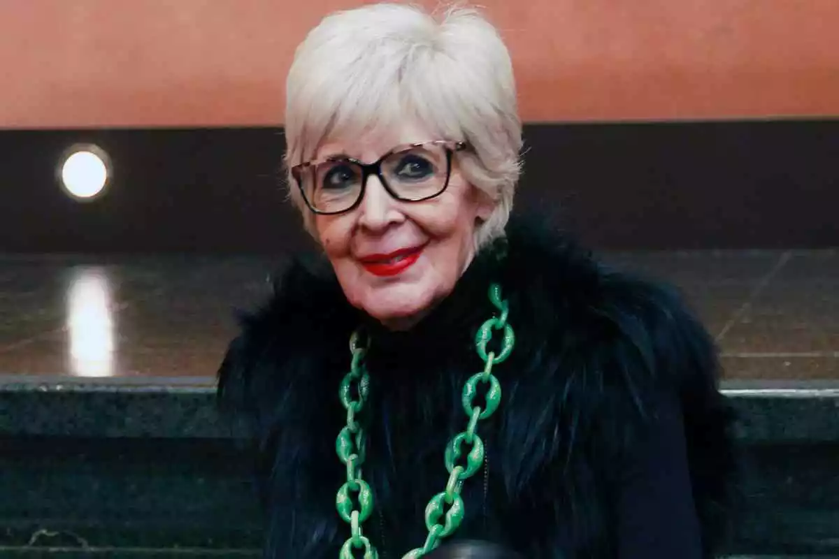 La actriz Concha Velasco con el pelo blanco y corto, vestida de negro con un collar de eslabones verdes y gafas oscuras