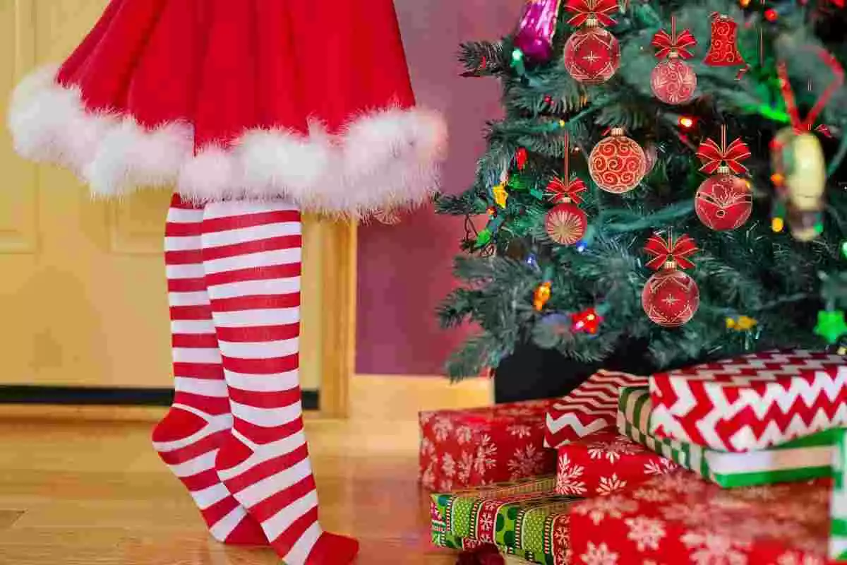 Mujer decorando un árbol de Navidad con regalos