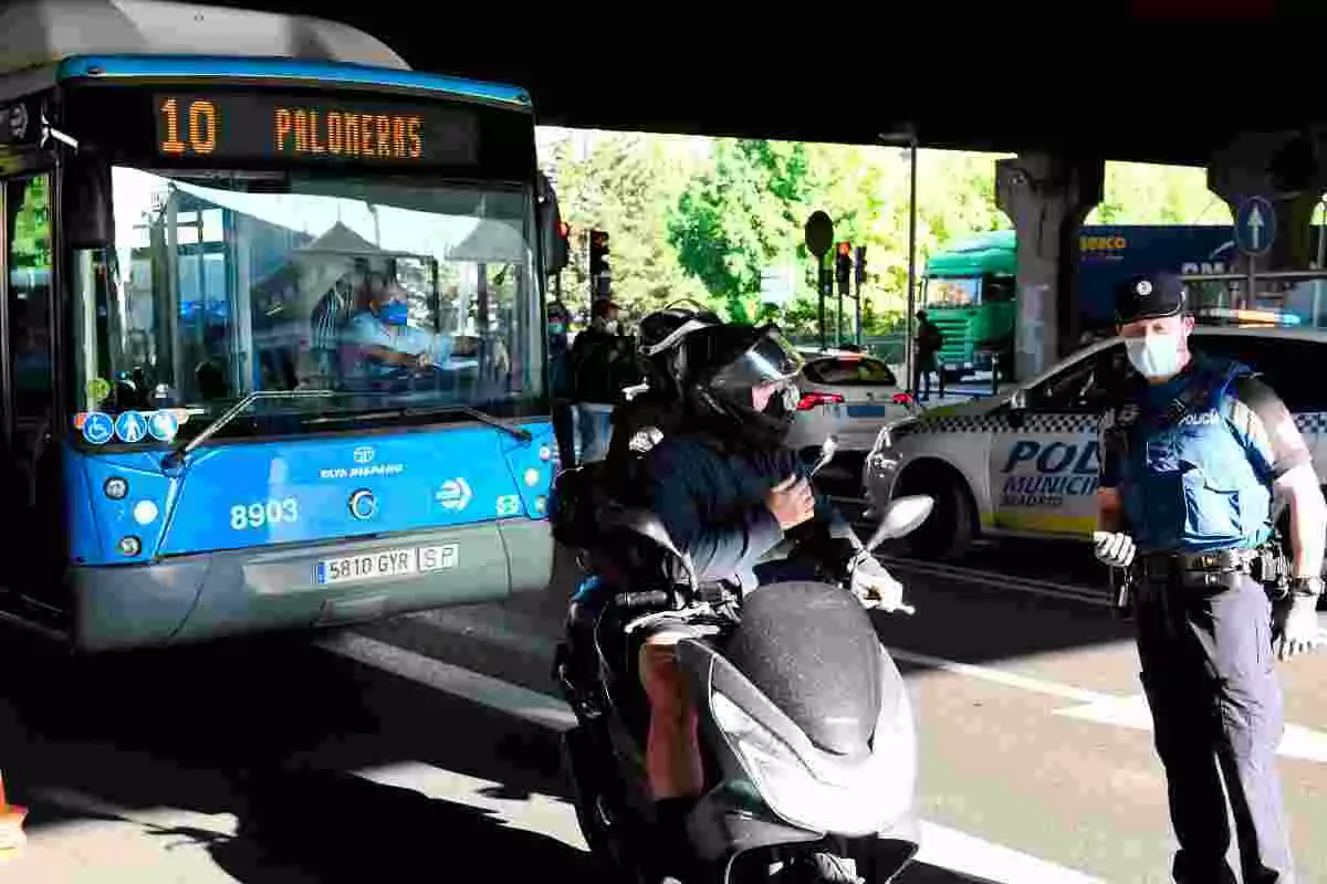 Policía Local de Madrid para a un motorista en un control de las restricciones de movimiento en Puente de Vallecas