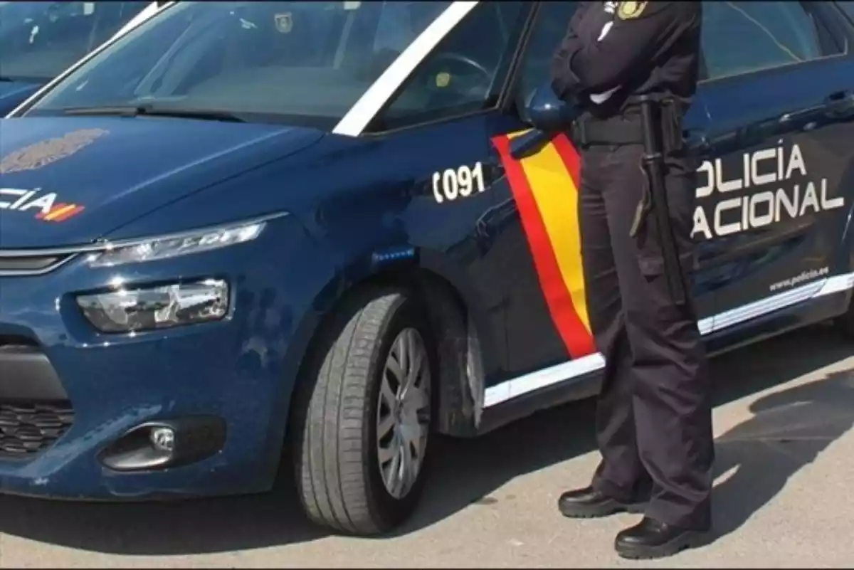 Un agente junto a un coche de la Policía Nacional