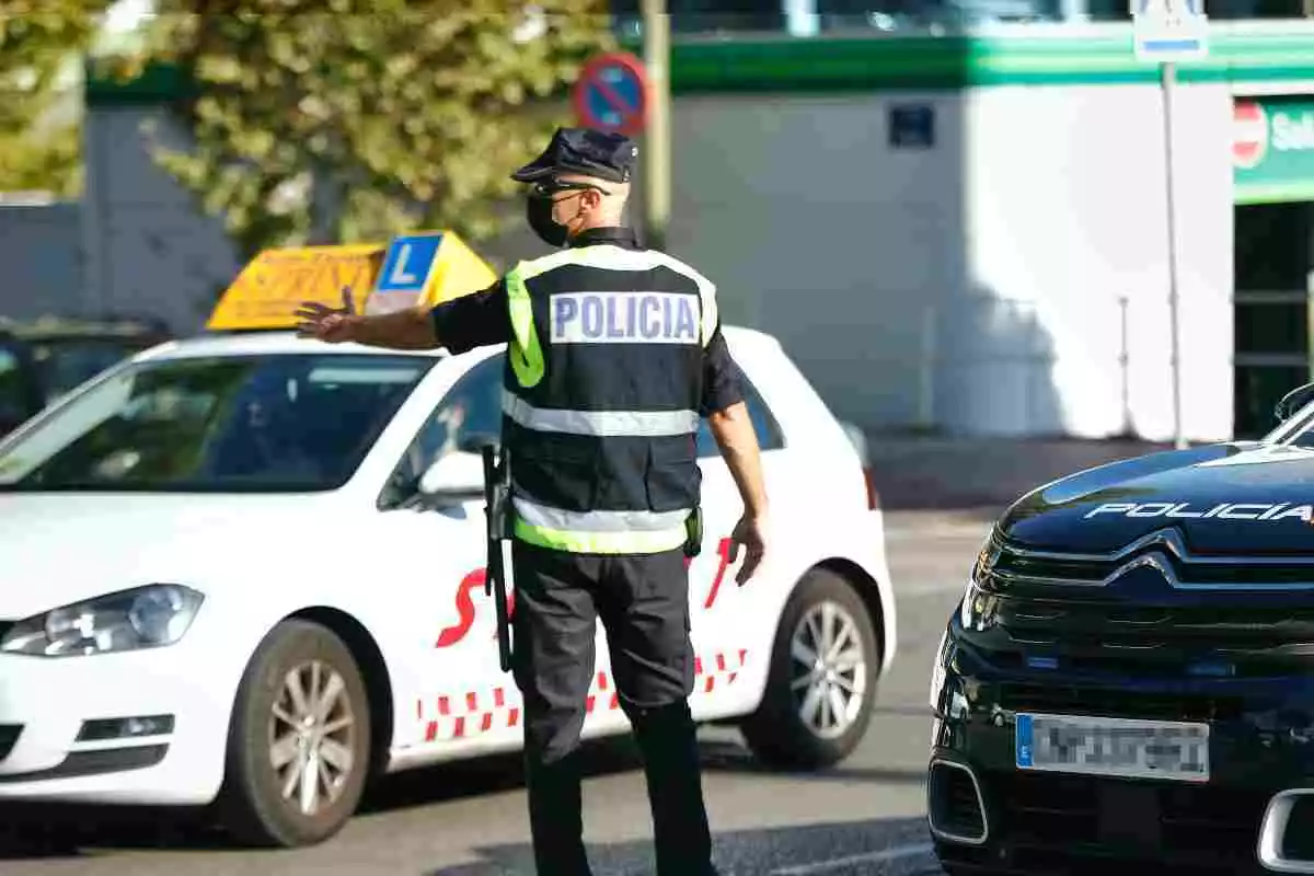 Agente de la Policía Nacional en un control en Móstoles parando un coche de autoescuela