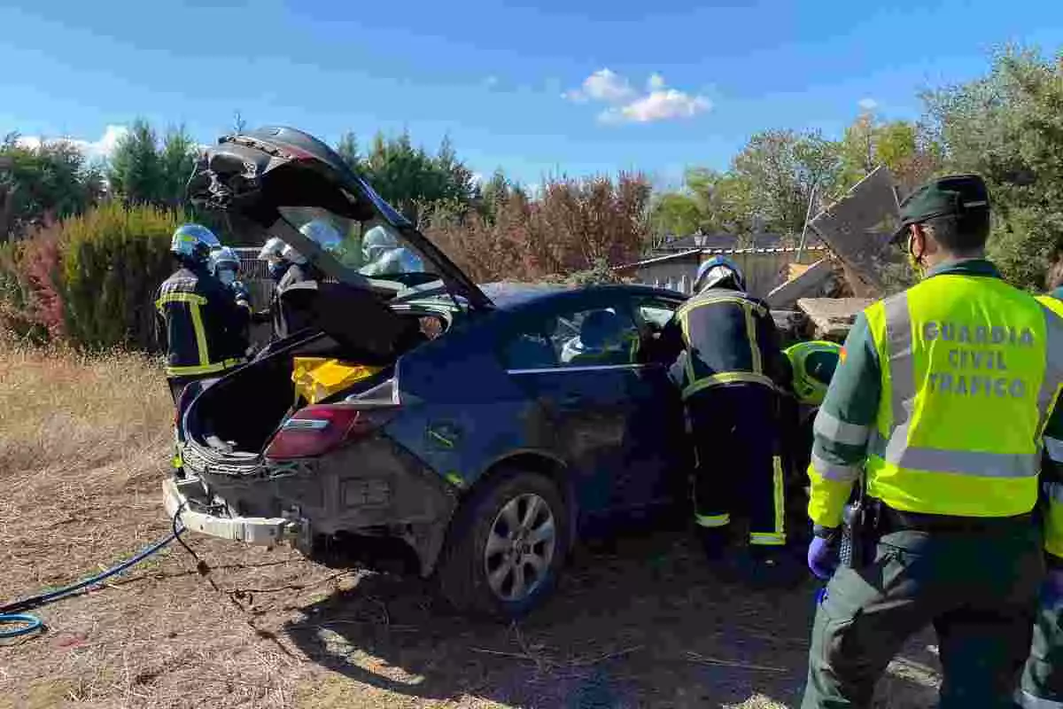 Bomberos y agentes de la Guardia Civil con un coche accidentado en Madrid