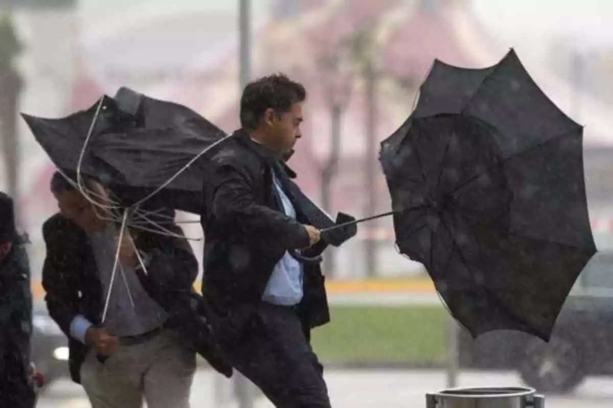 Imagen de un hombre aguantando su paraguas en pleno temporal