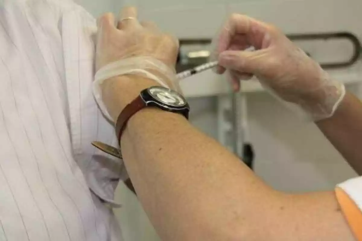 Plano de detalle de un profesional sanitario aplicando una vacuna en un paciente