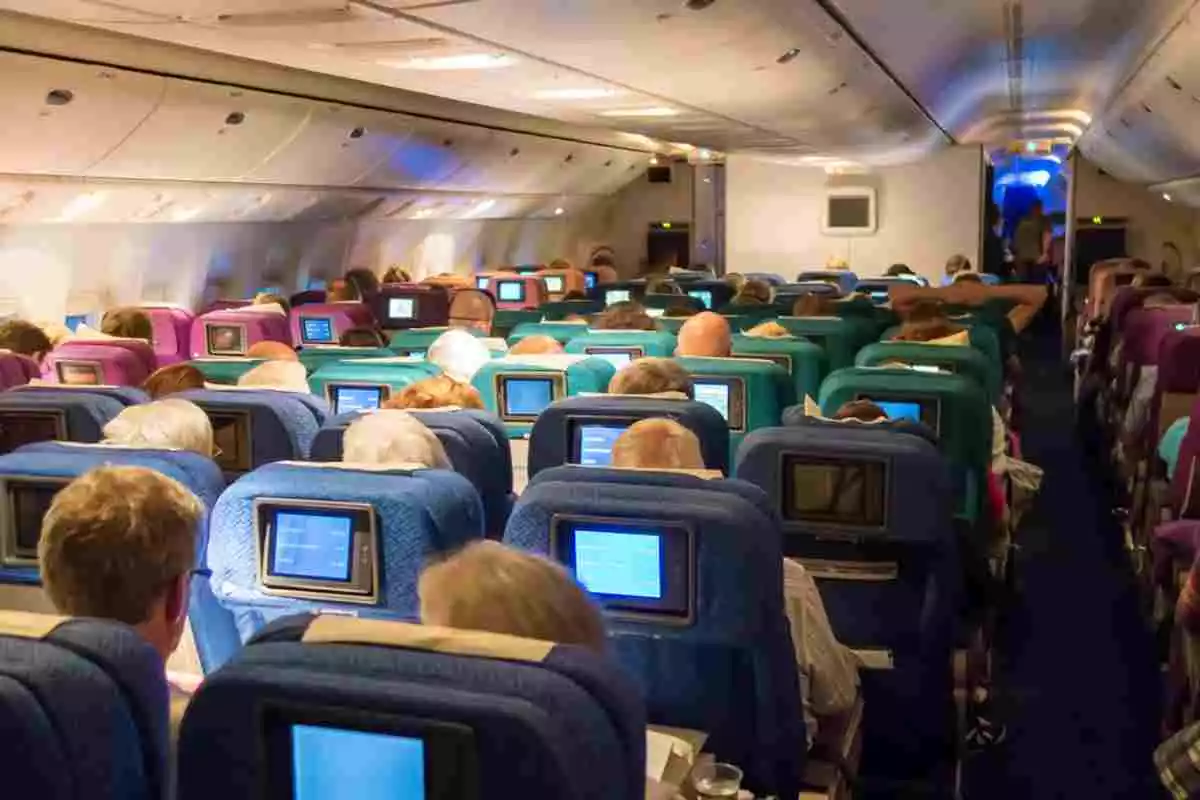 Vista trasera de los pasajeros sentados en sus asientos en el interior de un avión