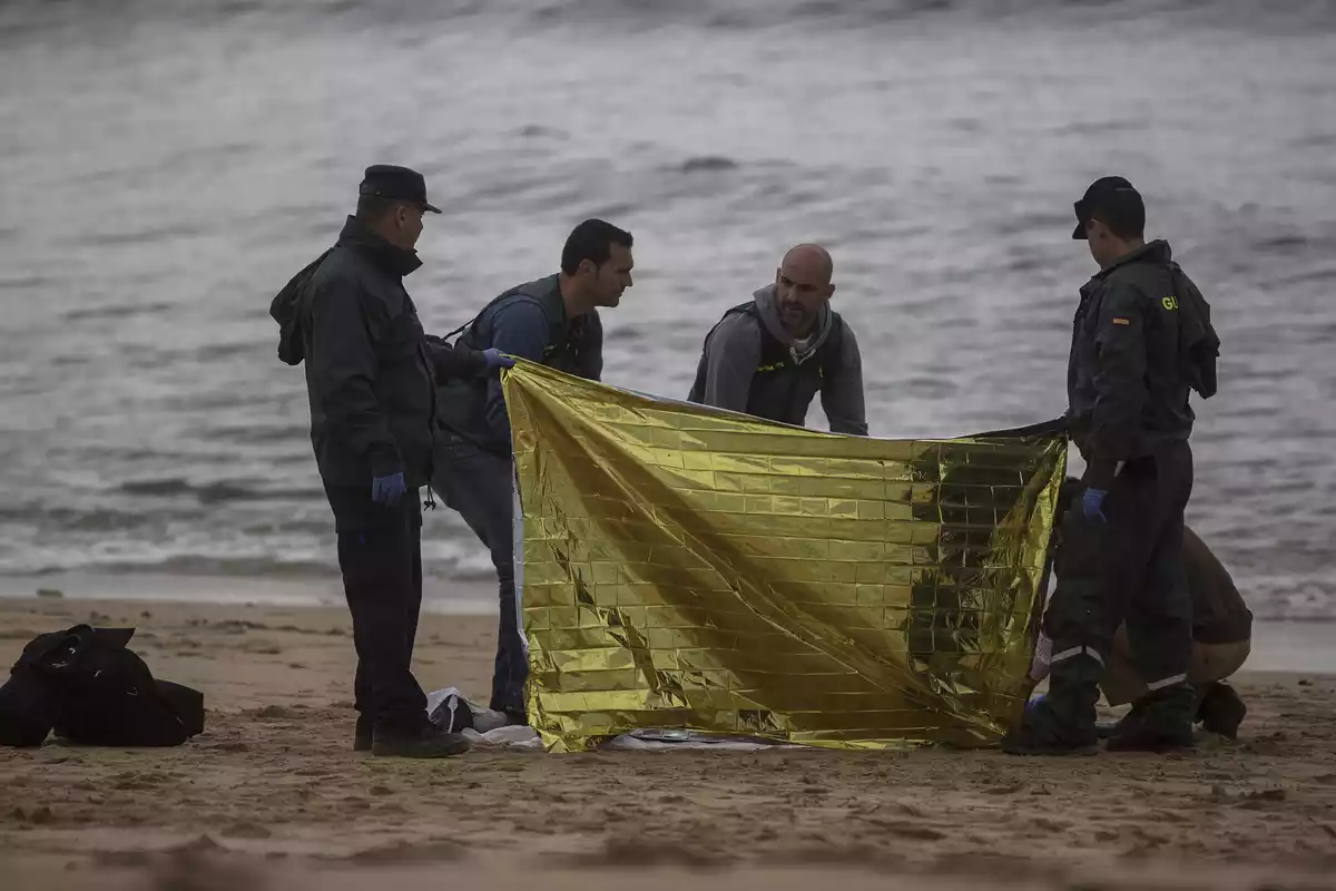 Agentes de la guardia civil cubriendo un cuerpo en la playa