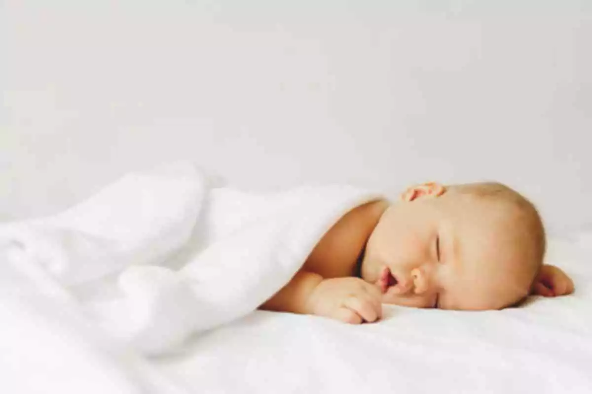 Bebé durmiendo y tapado con una sábana blanca