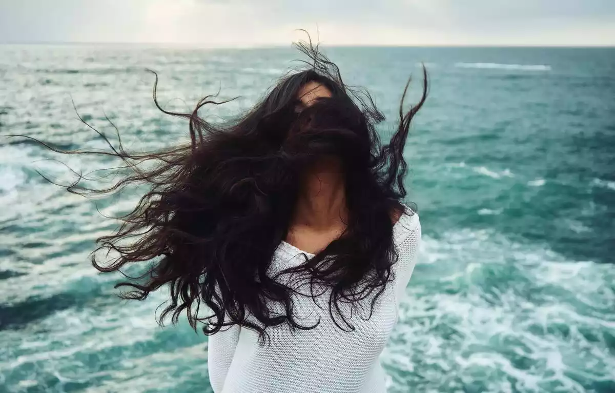 chica con el pelo al viento con el mar de fondo