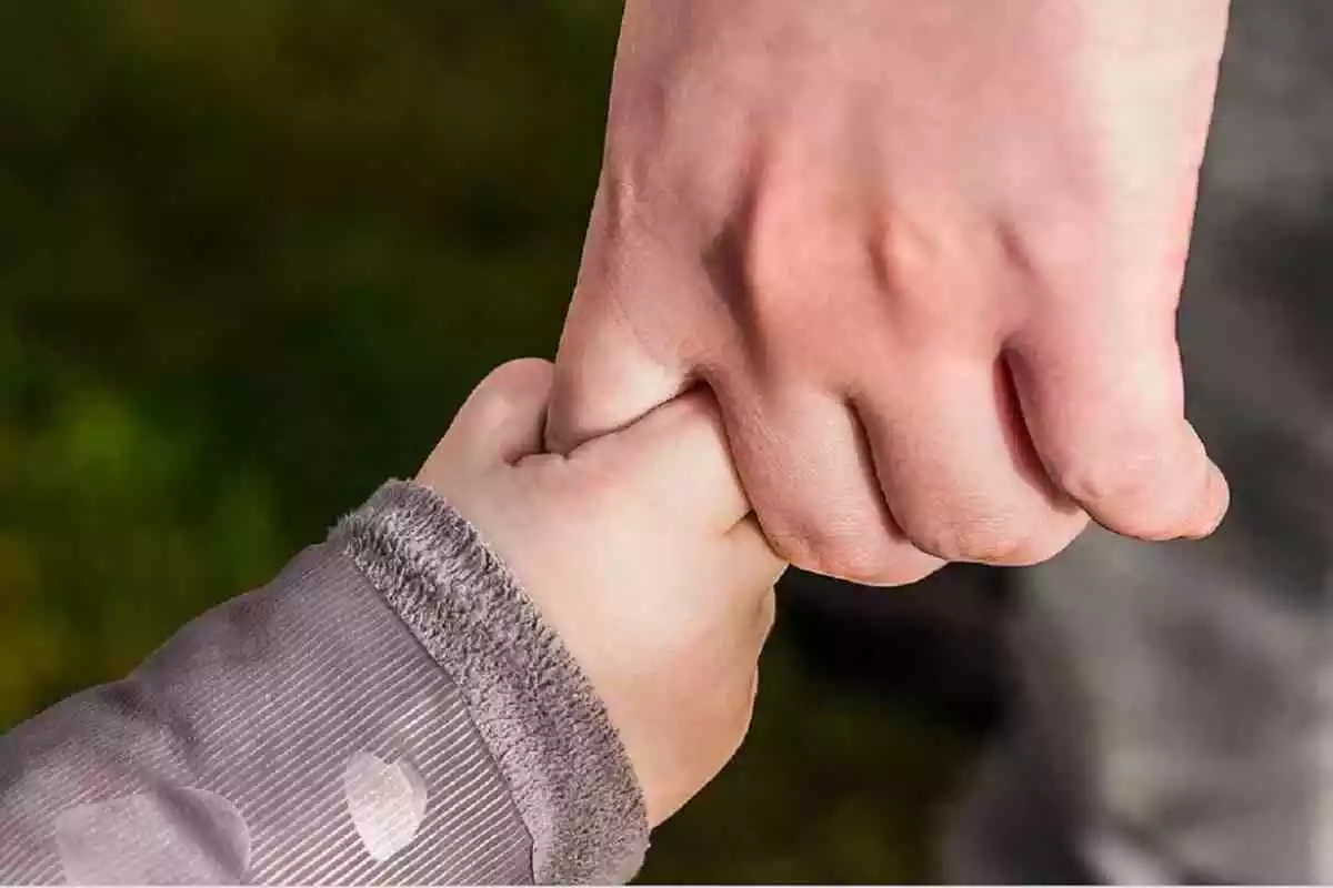 Mano de una niña pequeña agarrando el dedo de un adulto