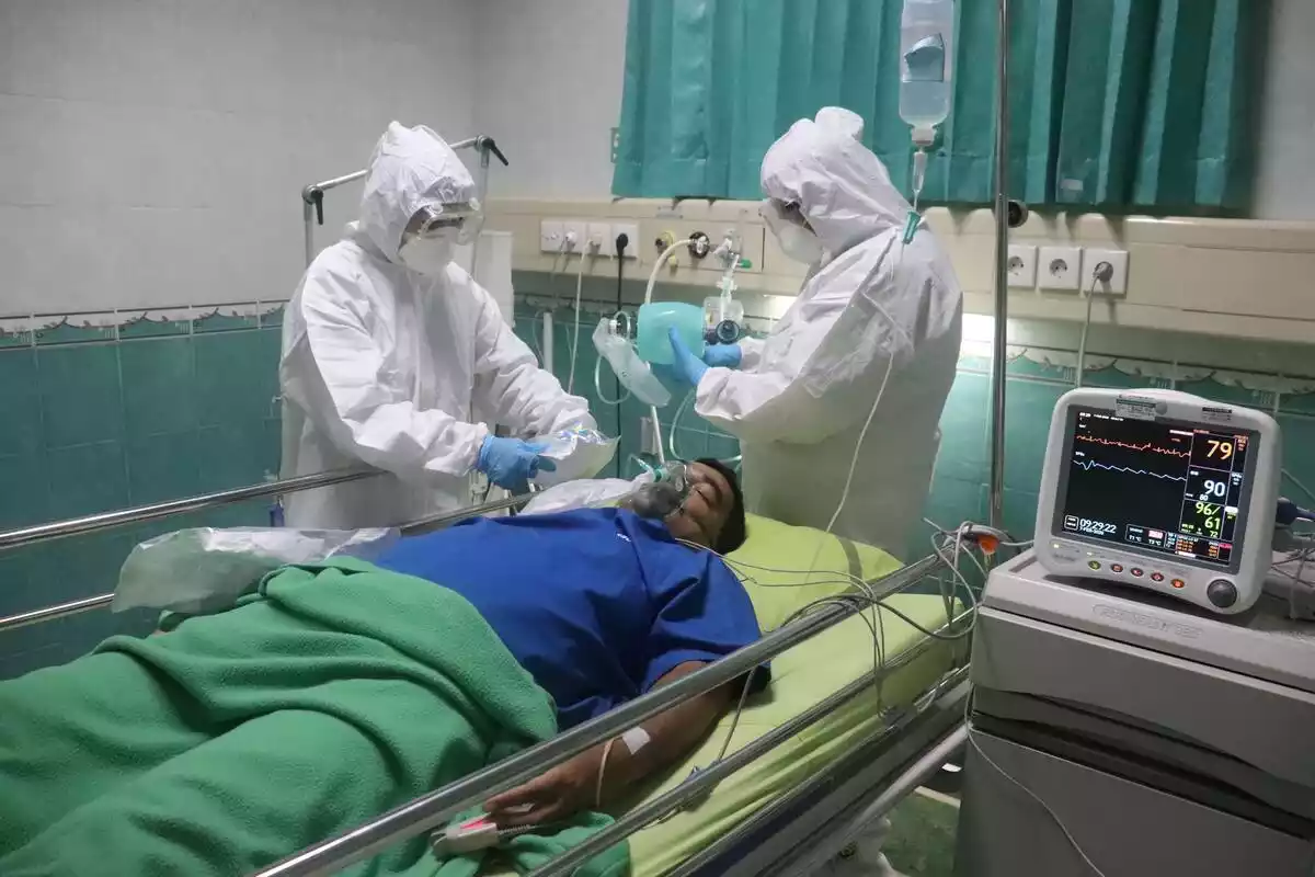 Paciente de Covid intubado y atendido por dos profesionales de la sanidad vestidos de blanco, altamente protegidos